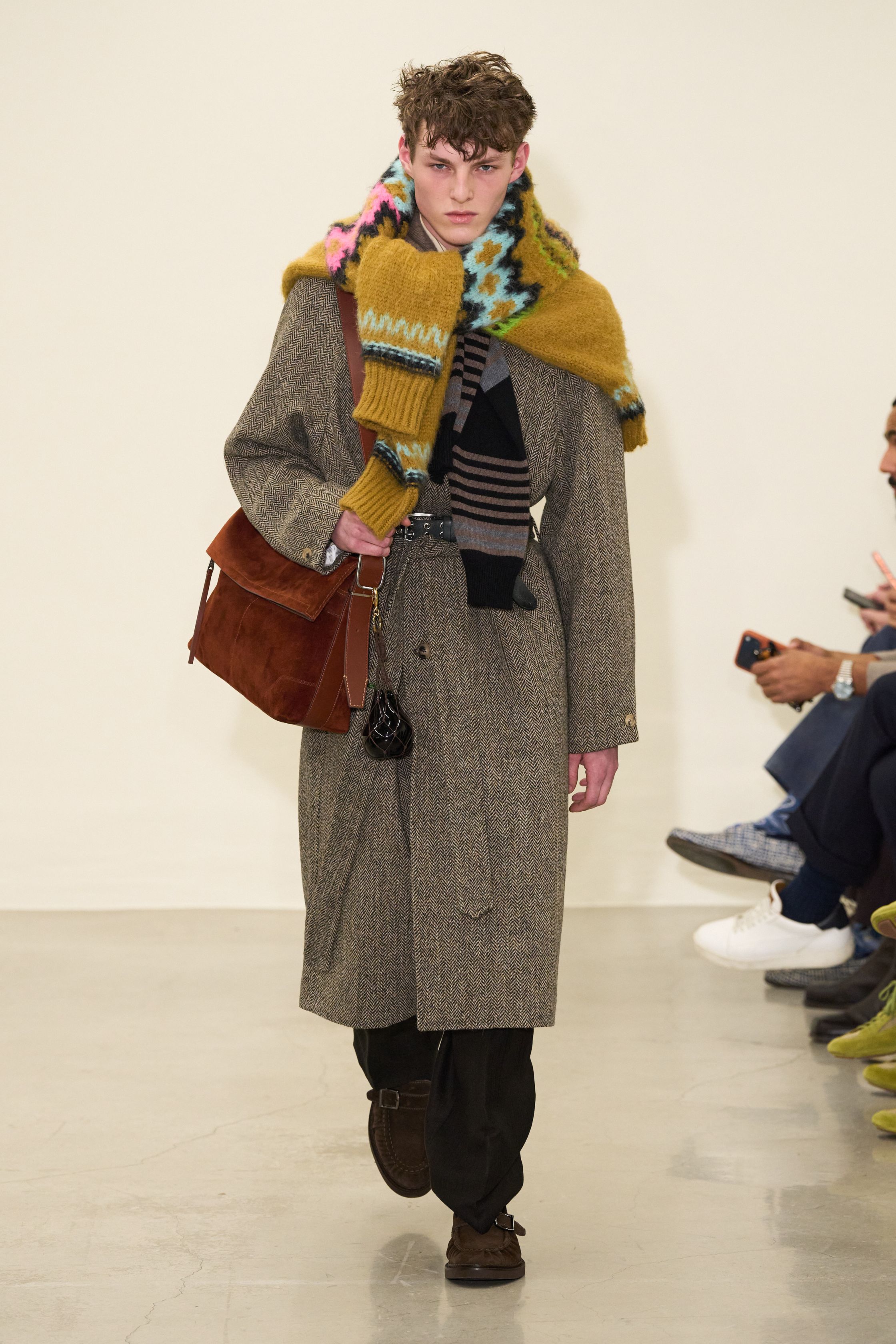 Paul Smith 2026秋冬回归品牌最具识别度的“英式日常诗意”。系列以传统剪裁为骨架，却通过色彩点缀、围巾叠搭与比例微调，赋予男装更松弛的情绪温度。西装不再严肃，风衣与大衣在肩线与长度上释放空间，搭配针织与衬衫形成轻度混搭。整体传递的是一种文化型男性的穿衣态度——不追逐潮流，却始终保持幽默感与个人风格-顽石频道趋势研究